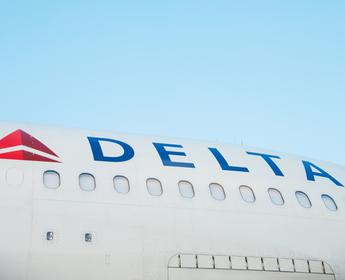 The side of a Delta aircraft against a blue sky
