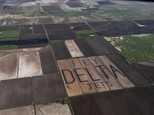 An aerial view of "Fly Delta Jets" carved into the field of a rice farm