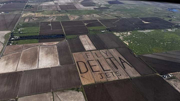 An aerial view of "Fly Delta Jets" carved into the field of a rice farm